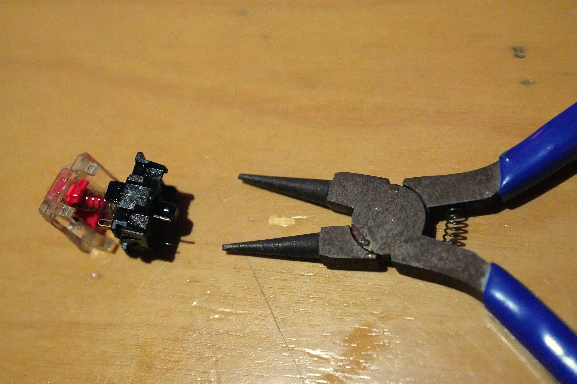 筐体の上下が分離されたキースイッチの隣に、先端が平たくなるよう加工されたプライヤが置かれている。