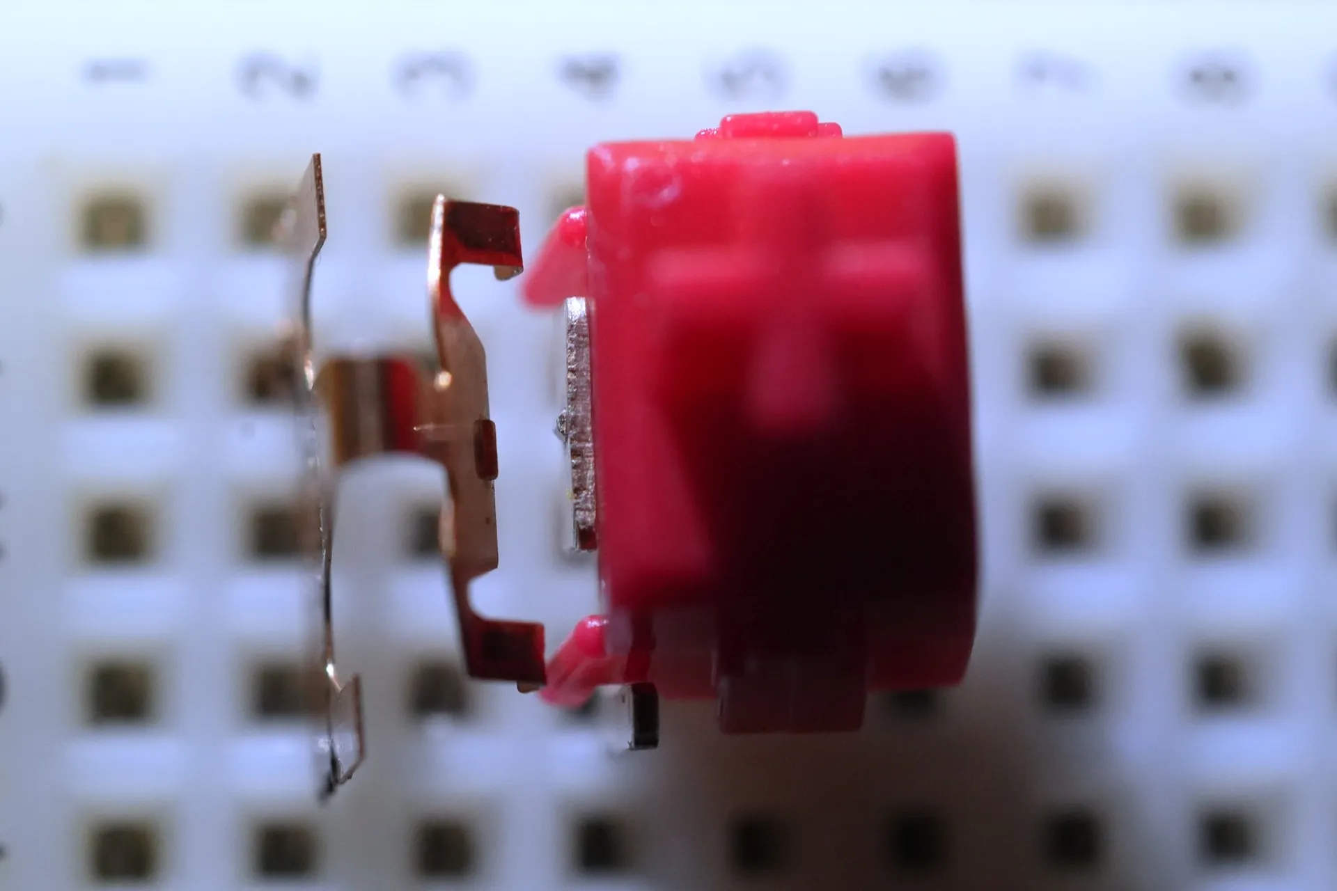 左側の金属部品が接点の両脇の2ヶ所で軸の部品に押されており、接点が右側の金属部品から離れている。